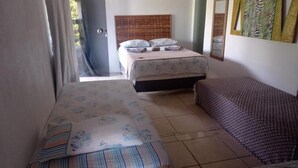 A bedroom with two beds, a wooden headboard, and a mirror on the wall. - Pousada Tulum (Maraú)