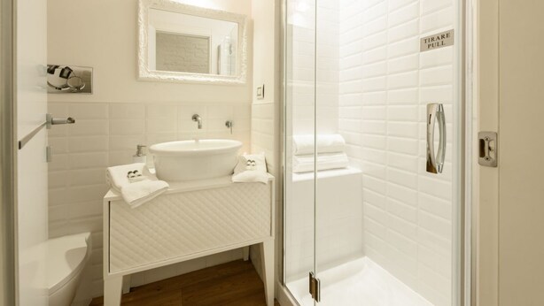 A modern bathroom with a white sink, toilet, and glass shower enclosure. - Don Giovanni apartment in Florence by Mmega (Florence)