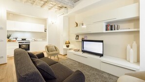 A modern living room with a sofa, TV, and a kitchen in the background. - Don Giovanni apartment in Florence by Mmega (Florence)