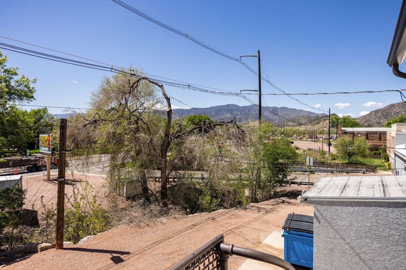 A view from a balcony overlooking a street with a mountain in the background.