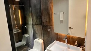 A modern bathroom with a glass-enclosed shower, a white toilet, and a large sink with a mirror above it. - Departamento a 20 metros de 5a Av. (Playa del Carmen)