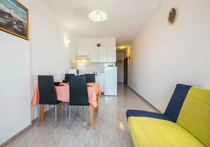 Cozy living space with a dining area and kitchenette, featuring a table, chairs, sofa, and refrigerator.