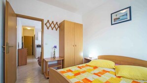 A bedroom with a bed, a desk, a wardrobe, and a door leading to another room. - Holiday apartment with air conditioning (Rabac)