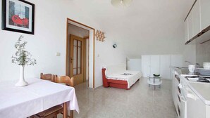 Um espaço compacto com área de refeições, minicozinha e cama.