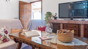 A cozy living room with a glass-top coffee table, a wicker basket, a book, and a wine glass. - Tere 2 Antequera - La Higuera by Ruralidays (Málaga)
