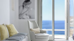 A modern living room with a grey armchair, a grey sofa, and yellow pillows. A large window offers a view of the sea. - Villa Magnolia  (Mykonos)