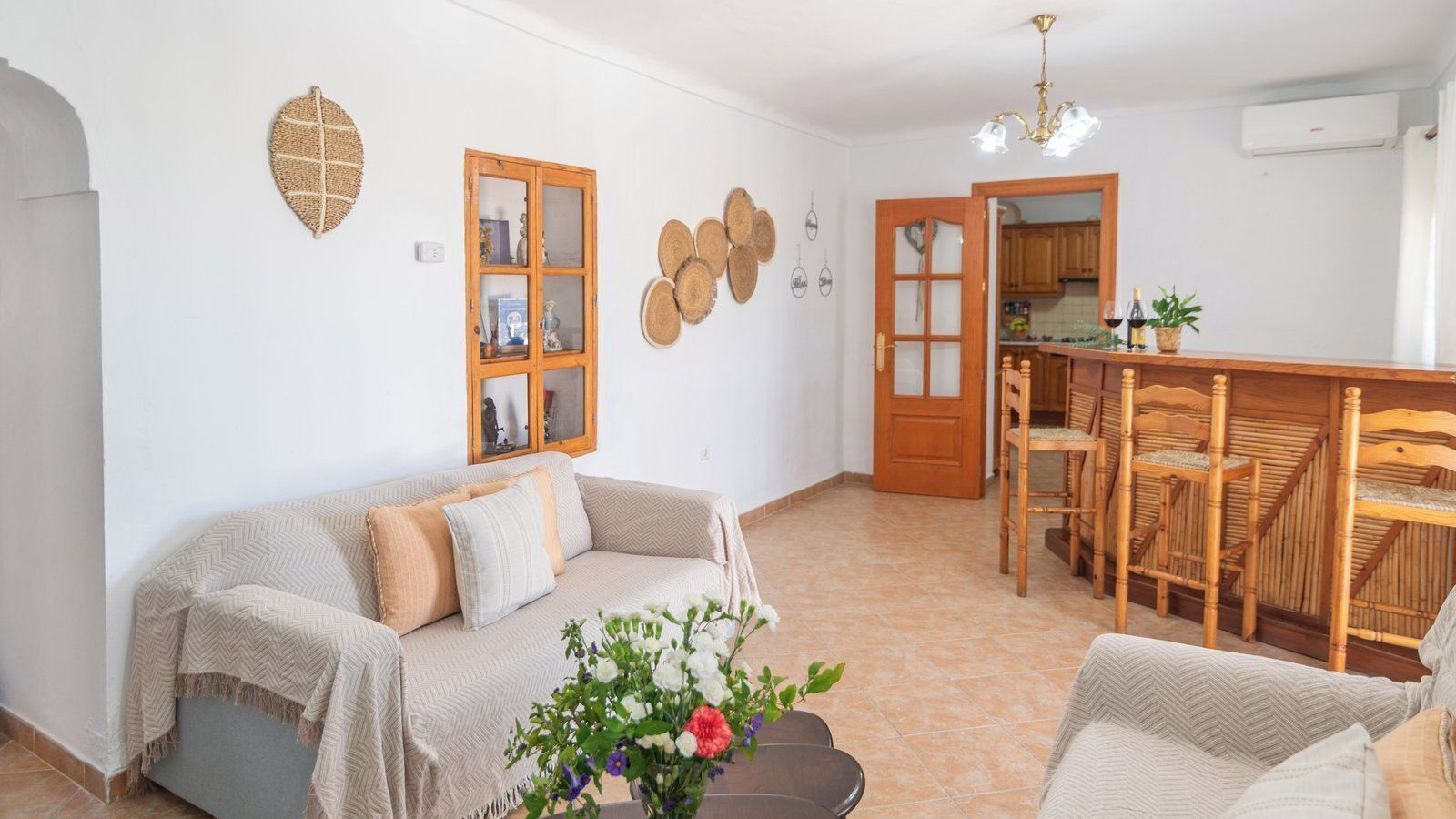 A cozy living room with a sofa, a dining table with chairs, and a kitchen area visible through an open door.