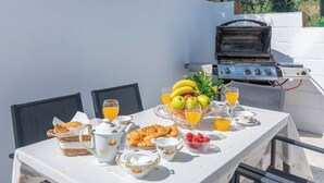 Aamiaiselle katettu pöytä, jolla on croissantteja, hedelmiä ja appelsiinimehua.