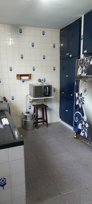 Ett kök med vita kakelplattor, en mikrovågsugn, en spis och skåp.