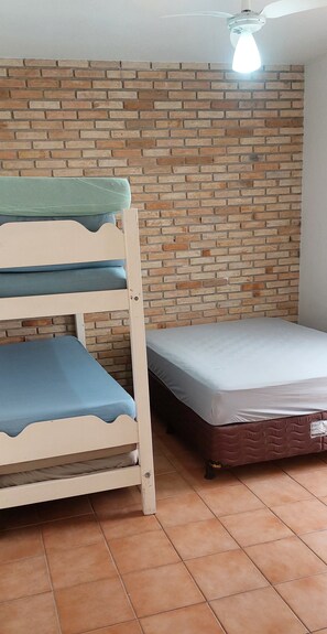 Cozy room with a bunk bed and single mattress, featuring a brick-patterned wall and ceiling fan.