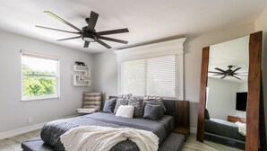 A bedroom with a bed, a ceiling fan, a large mirror, and a window with blinds. - Modern Delray Beach Charmer - Near Atlantic Ave. in Delray Beach (Delray Beach)