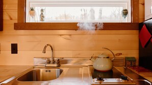 Une cuisine équipée d’un évier en acier inoxydable, d’une cuisinière à gaz et d’une fenêtre située au-dessus de l’évier.