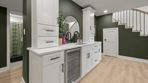 A modern kitchen with white cabinetry, a built-in dishwasher, and a large window. - King Beds <> A Sumptuously Lavish Suite Xcape (Alexandria)