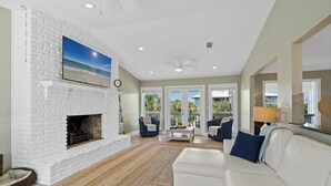 A living room with a white brick fireplace, a white sofa, and a large window overlooking a balcony.
