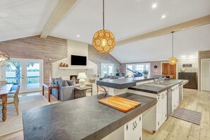 A spacious kitchen with a large island, wooden ceiling beams, and a modern pendant light. - Stay Salty: 6BR East Beach Escape | Pool + Sunset Marsh Views (Saint Simons Island)