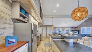 Una cuina moderna amb una illa central, electrodomèstics integrats i un llum penjant.