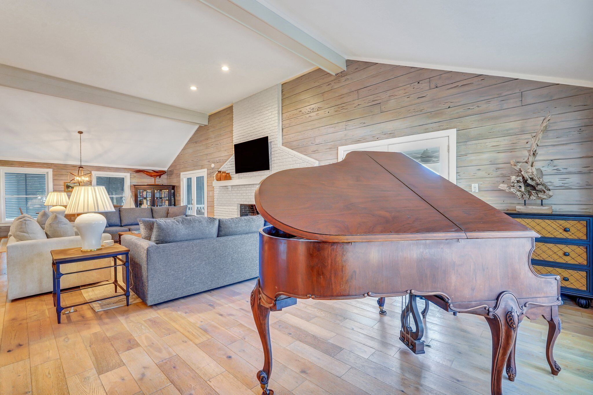 A spacious living room with a grand piano, a fireplace, and a cozy seating area.