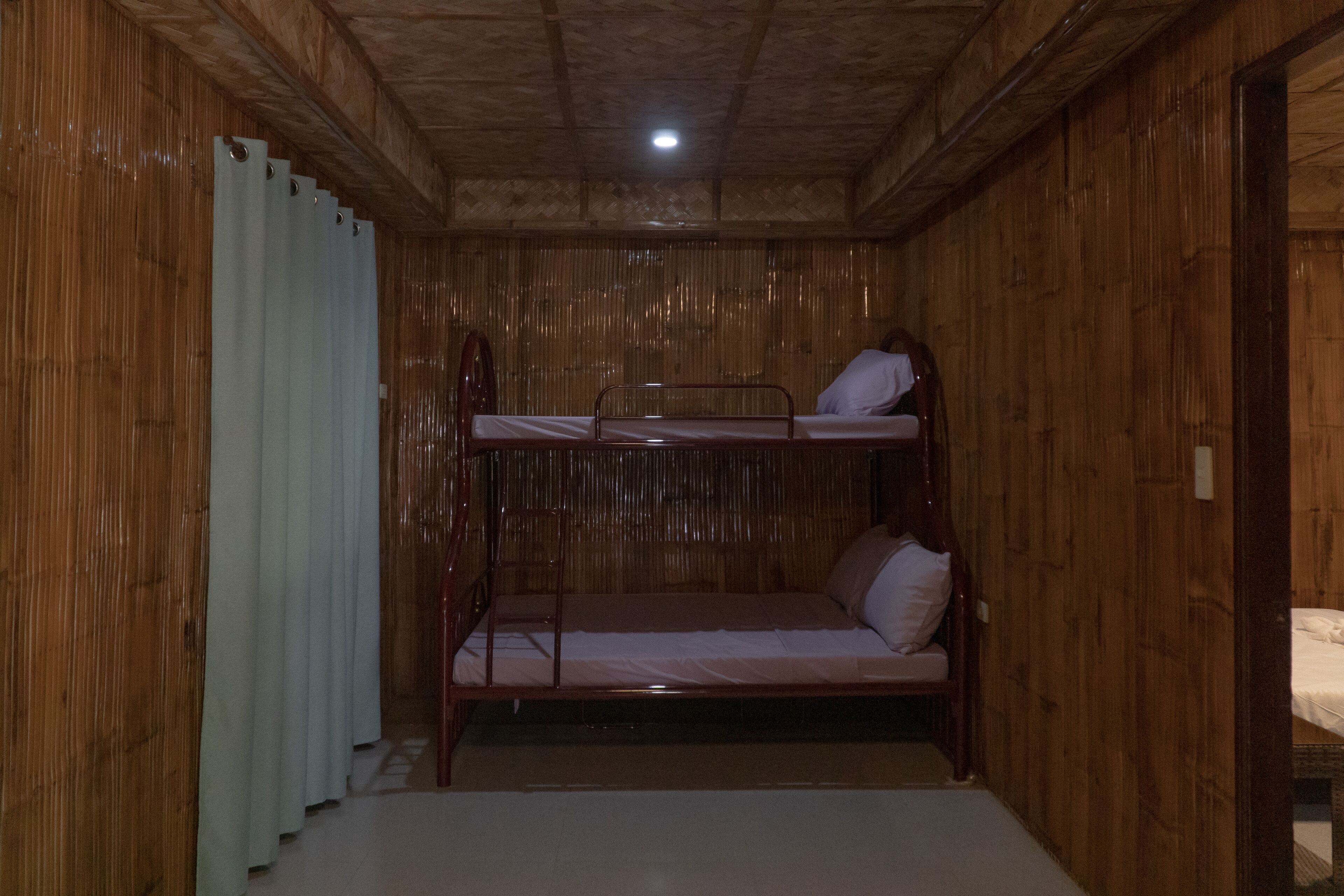 A bunk bed room with wooden walls and a single bed at the bottom.