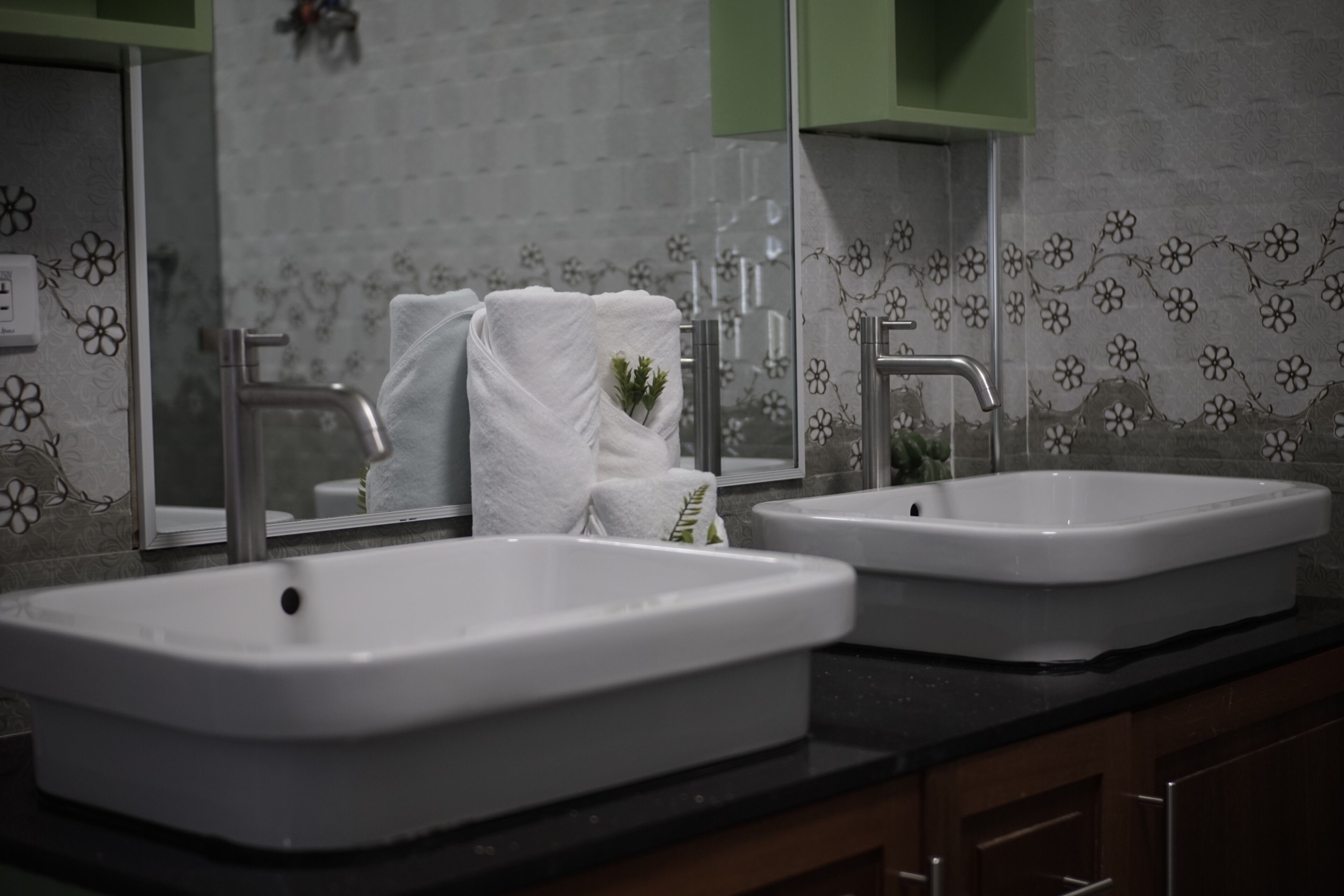 Un baño con dos lavamanos, un espejo y un perchero para toallas.