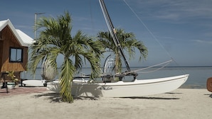 Ein Strandhaus mit einem großen Teleskop, Palmen und einem Boot im Sand.