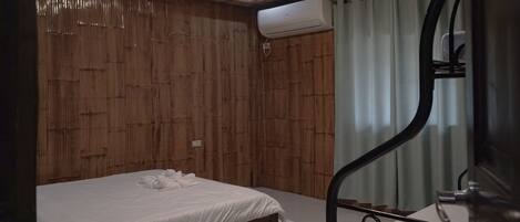 A bedroom with a wooden wall, a bed with white bedding, a metal staircase, and an air conditioning unit.