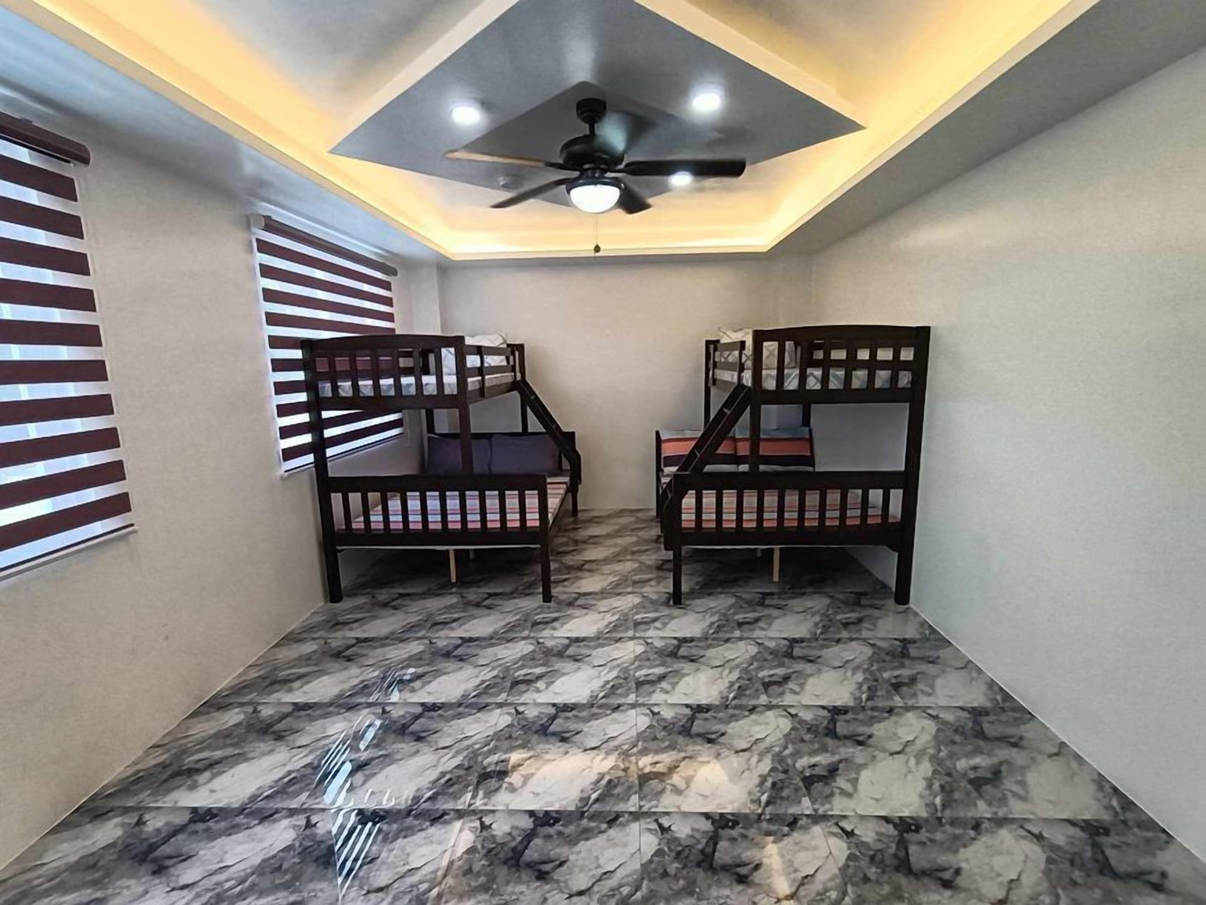 A room with two bunk beds, a ceiling fan, and a skylight.