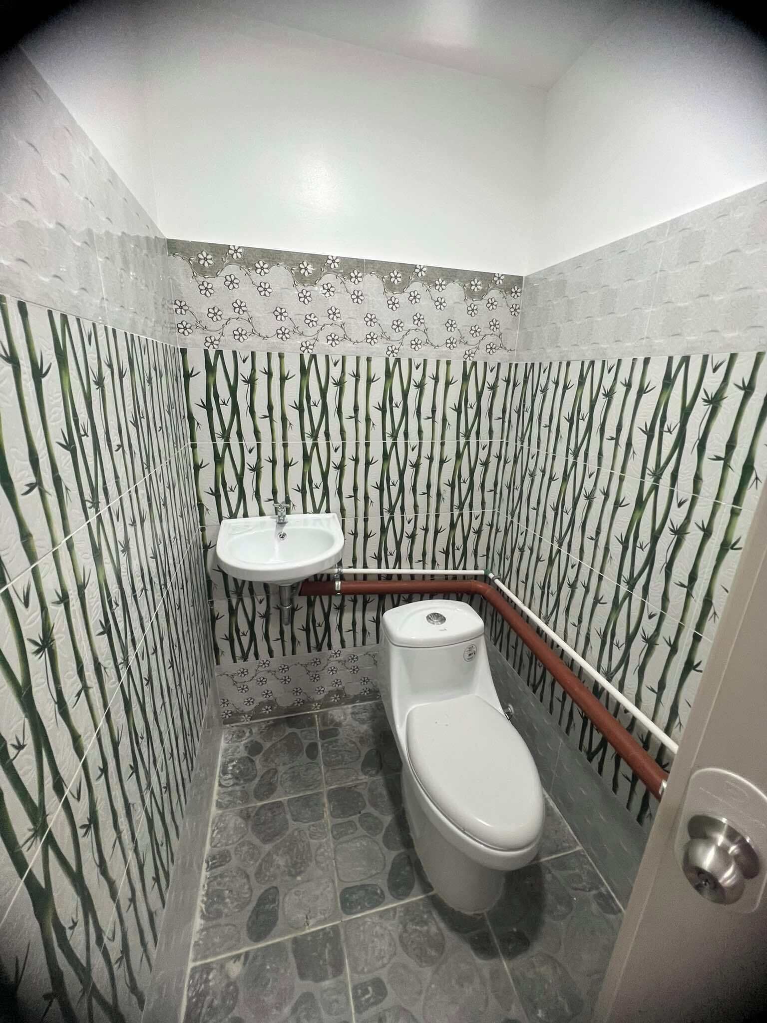 A bathroom with a toilet, a sink, and patterned walls.