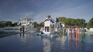 Ein Wasserpark mit Schwimmbecken, Wasserrutschen und Spielgeräten.