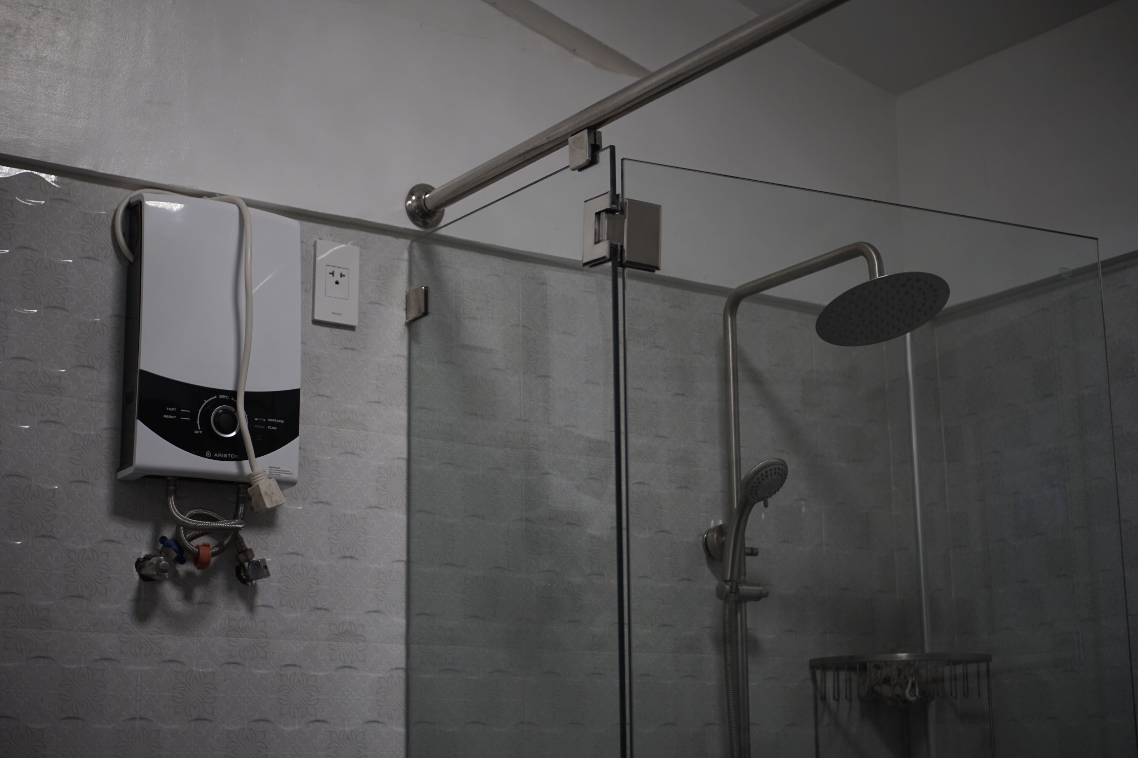 A modern shower area with a glass enclosure, a handheld showerhead, and a wall-mounted control panel.