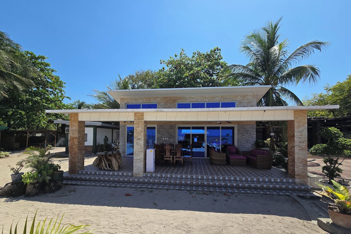 A modern building with a covered patio area, outdoor seating, and a water dispenser.