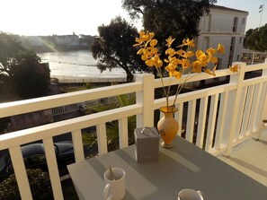 A balcony with a table, a vase with yellow flowers, and a box labeled "BISCUITS". - Saint Palais sur Mer - SUPERB INFINITELY RARE APARTMENT - LE PHALENE (ST PALAIS SUR MER)