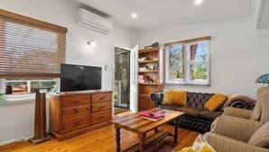A living room with a wooden cabinet, a television, a sofa, and a coffee table. - Blue Haven Gypsy Paradise - Cottage plus caravans (Blue Haven)