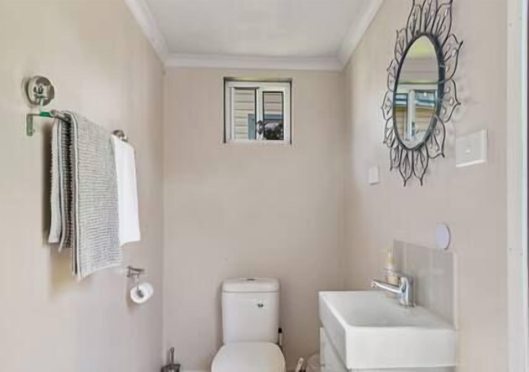 Een badkamer met toilet, wastafel en een klein raam.