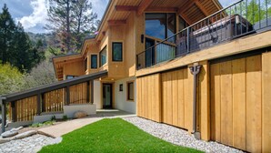 Ett modernt trähus med en balkong, stora fönster och en välskött gräsmatta.