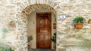 Un bâtiment en pierre avec une porte en bois, des plantes en pot et une boîte aux lettres.