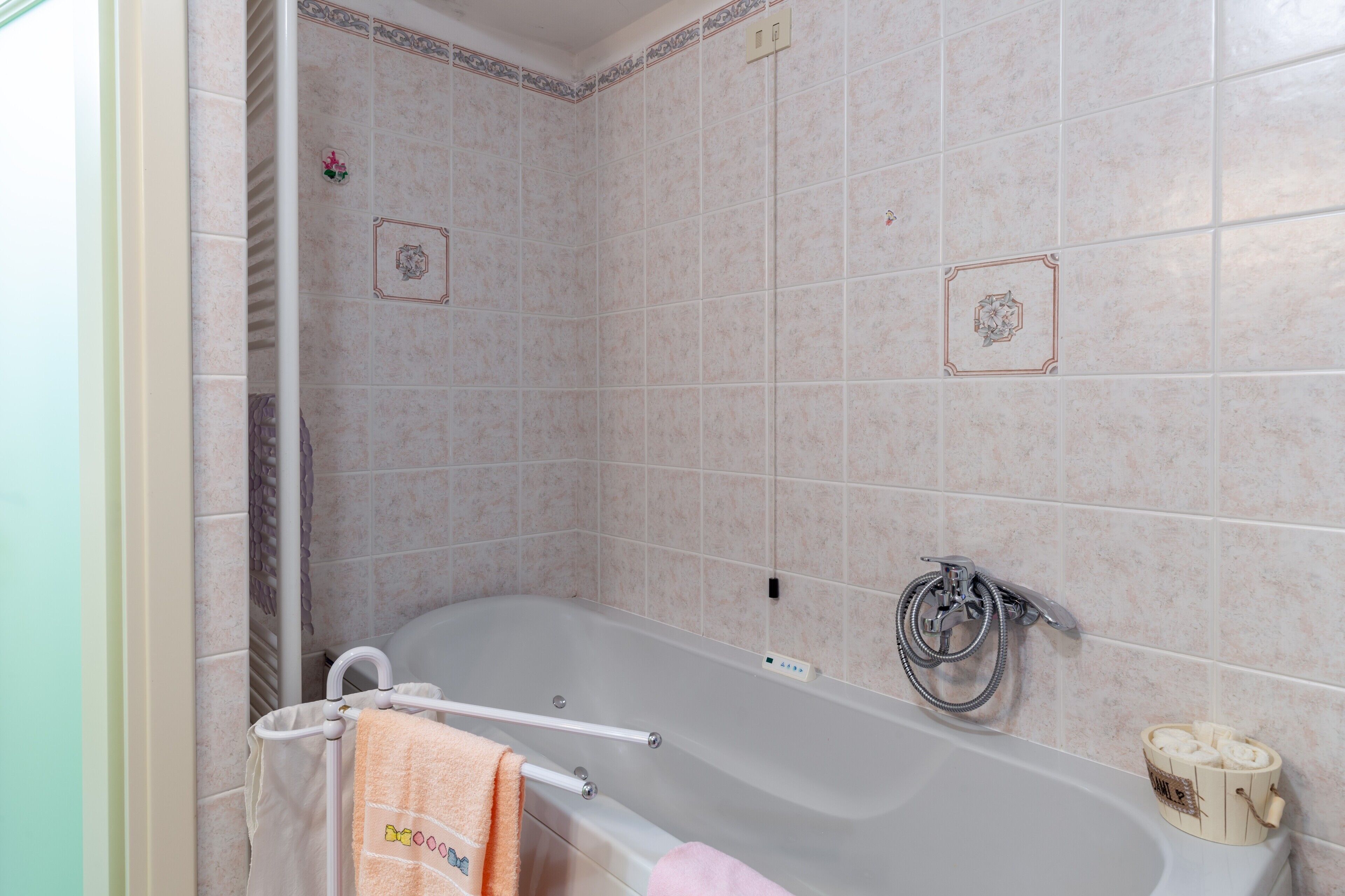 Een badkamer met een bad, een handdoekrek met handdoeken en een toiletpapierhouder.