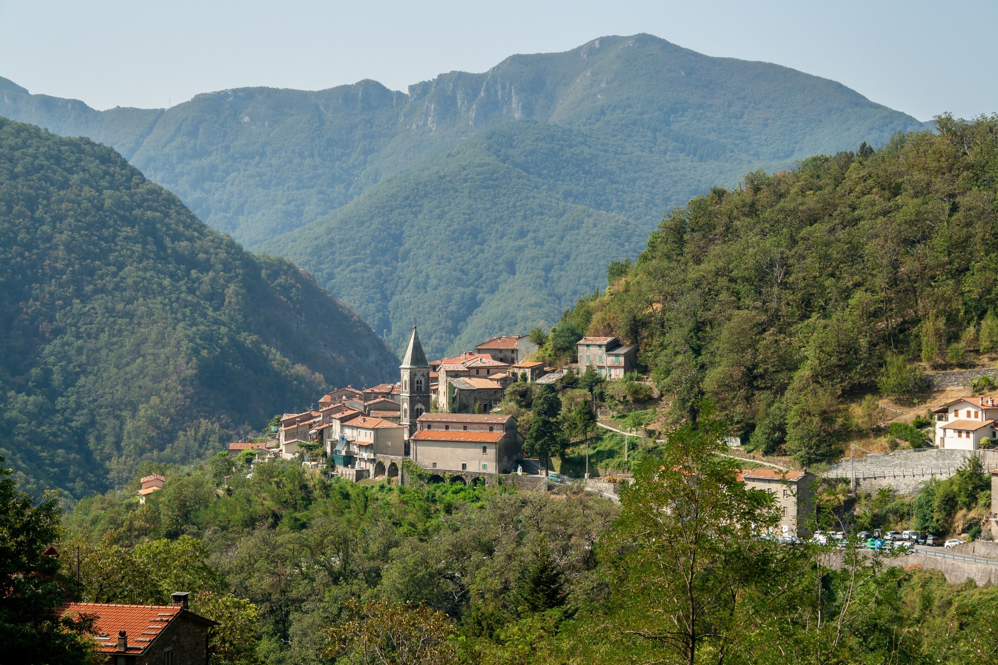 A mountainous village with traditional architecture, a church, and a stone wall.
