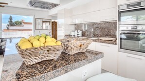 Una cucina moderna con piani in granito, elettrodomestici in acciaio inossidabile e cesti di vimini sull'isola.