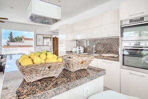 Una cocina moderna con encimeras de granito, electrodomésticos de acero inoxidable y cestas de mimbre en la isla.
