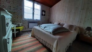 Een slaapkamer met een bed, een bureau, een stoel, een radiator en een raam.
