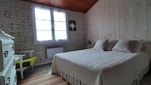 Un dormitorio con cama, cómoda, ventana y radiador.