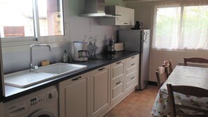 Een keuken met een Bosch wasmachine, een spoelbak, een koffiezetapparaat en een eettafel met stoelen.