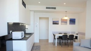 A compact kitchen with a microwave, a dining area with a table and chairs, and a sofa. - Apartment 'Residence Bafjle 42' with Shared Pool, Private Terrace and Air Conditioning (Jesolo)