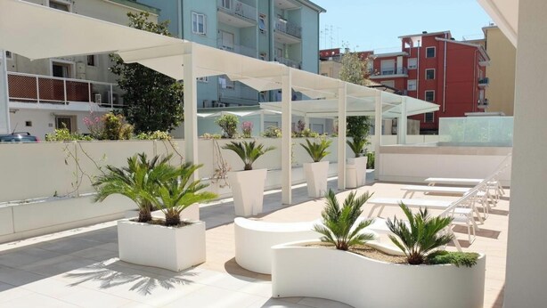 A rooftop terrace with white planters, lounge chairs, and a covered seating area. - Apartment 'Residence Bafjle 42' with Shared Pool, Private Terrace and Air Conditioning (Jesolo)