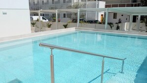 A clear swimming pool with a metal safety railing, surrounded by a white building with balconies and potted plants. - Apartment 'Residence Bafjle 42' with Shared Pool, Private Terrace and Air Conditioning (Jesolo)