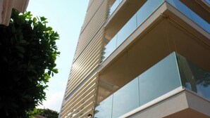 A modern building with a glass facade, horizontal lines, and a balcony.