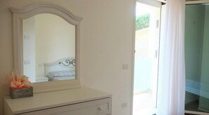 A bedroom with a bed, a dresser, a mirror, and a window with curtains. - Apartment 'Torre Gidone 2' with Sea View, Private Terrace and Air Conditioning (Lido di Jesolo)