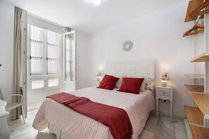 Une chambre à coucher comprenant un lit, des tables de chevet, une chaise et une armoire.