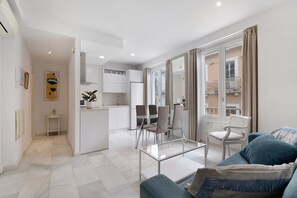 A modern living room with a glass coffee table, a sofa, and a dining area with chairs.
