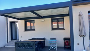A covered outdoor area with a table and chairs, a small blue chair, and a fire extinguisher. - Villa Rascola Piscine 4 Stars with private pool, Wi-Fi and air conditioning (Le Boulou)